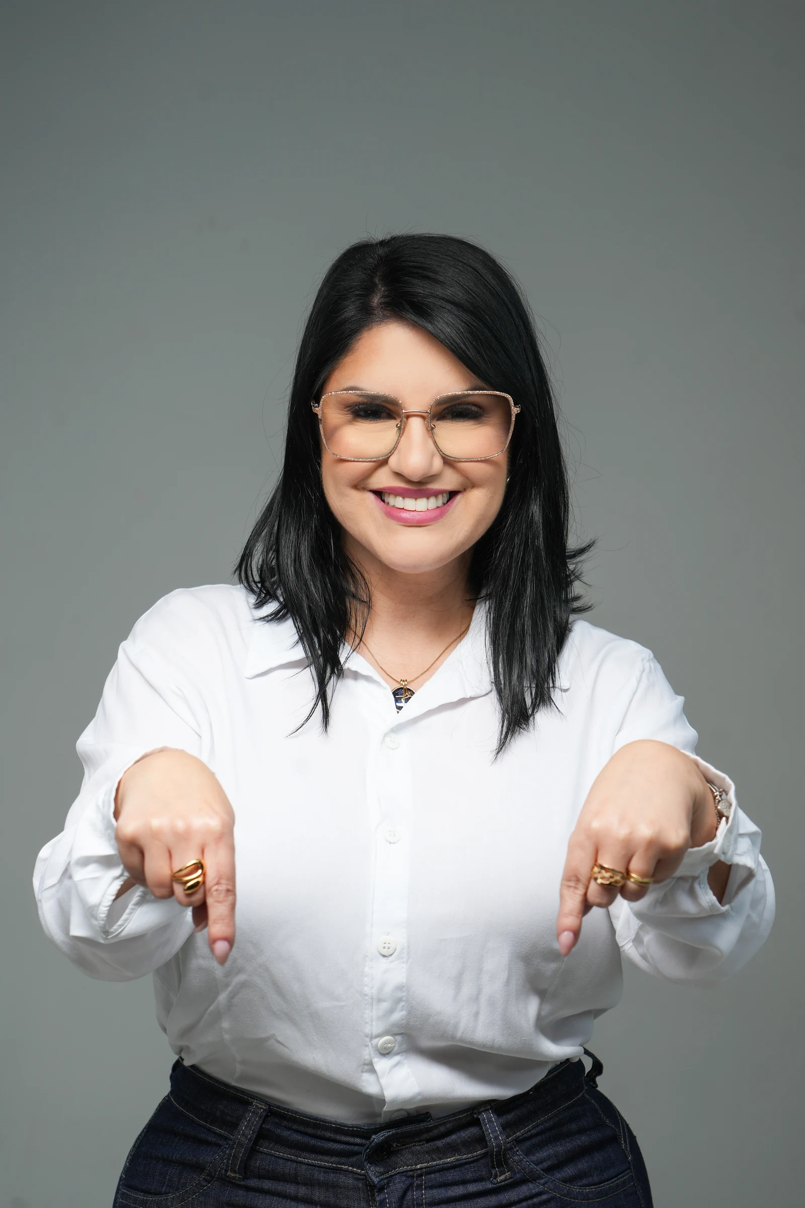 Fabi Medeiros sorrindo e apontando para baixo